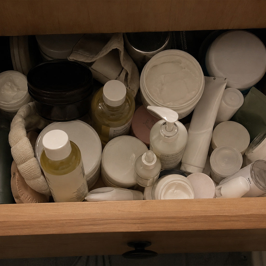 A drawer of partly used skincare bottles